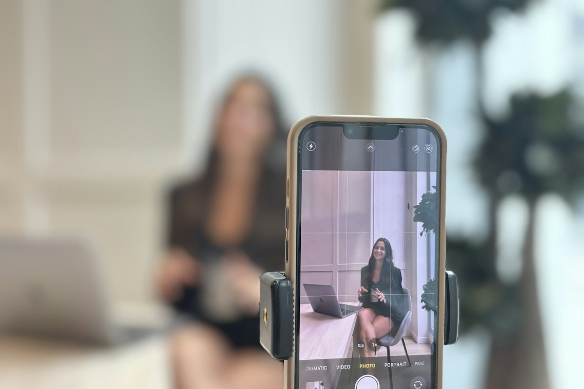 Smartphone on a tripod filming a woman presenting at a desk