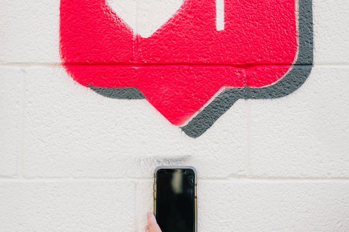 Painted heart 'like' icon on a white wall above a phone